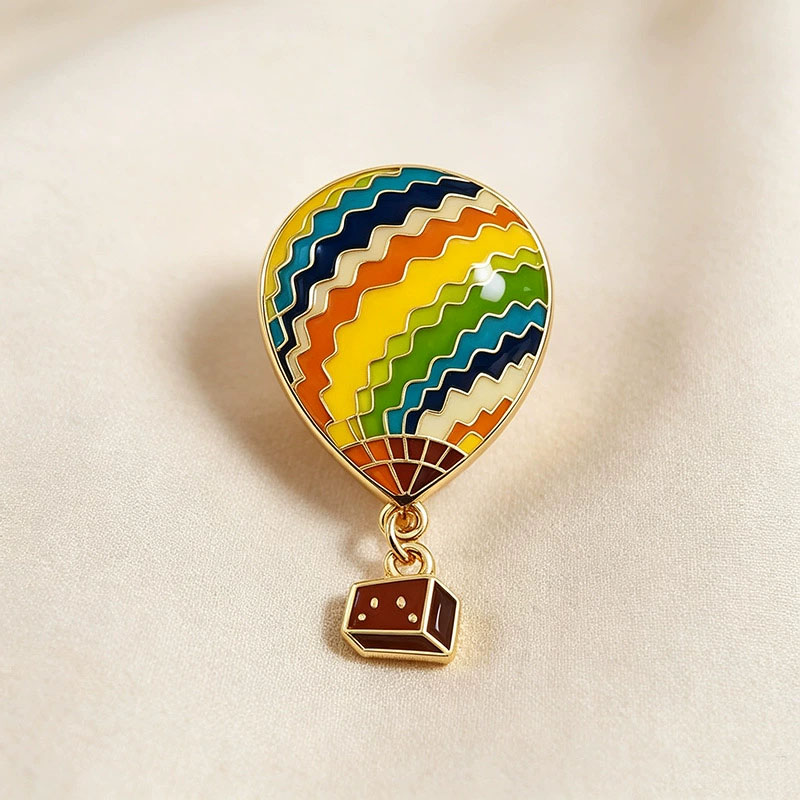 Embroidery Bali - Heißluftballon-förmige Metallbrosche, Merchandise aus dem Album